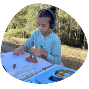 Girl works on Oak Meadow curriculum outdoors 